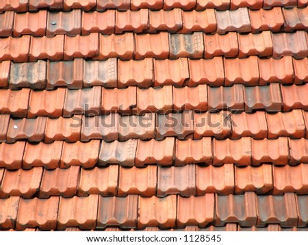 Red and orange roof tiles on an Italian residential building in a small town. Ceramic slate roof.