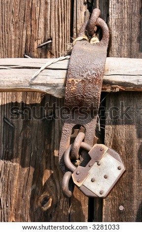 Wooden door to a warehouse and a metal pad lock. Closed and secure.