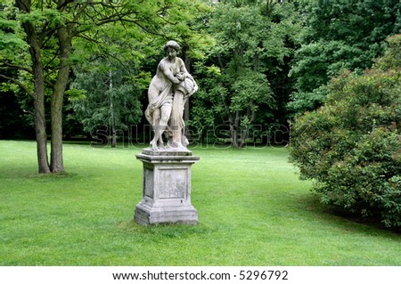 Lazienki - Royal Park in Warsaw, Poland. Green lawn, trees and a classical statue.