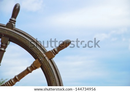 old ship wheel with blue sky background