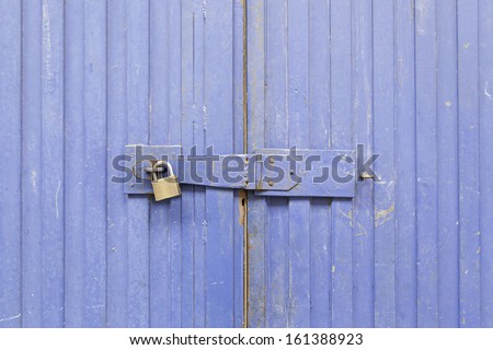 Blue door padlocked, detail of an old door painted blue, safety and security