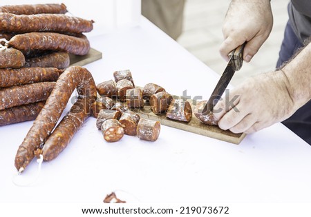 Cutting sausage with a knife, detail of a chef cutting food