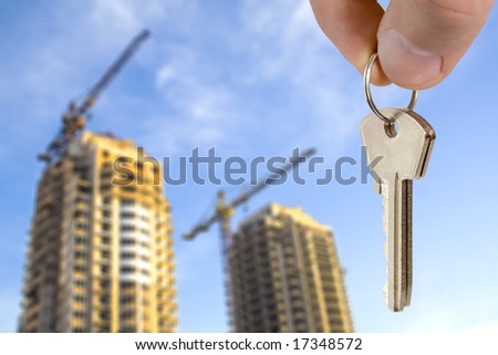 real estate concept. key in fingers with houses