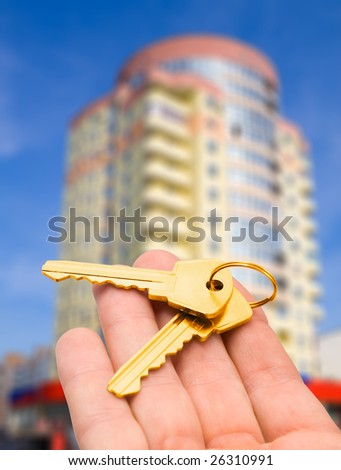real estate concept. gold key in fingers with new houses