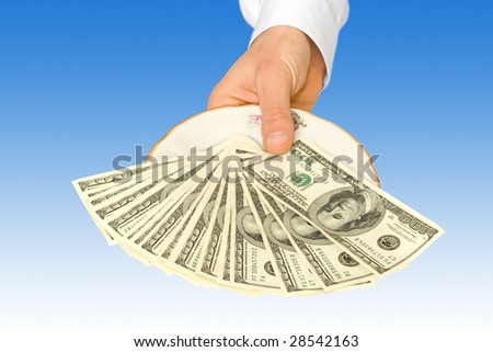 money on plate with hand over blue background