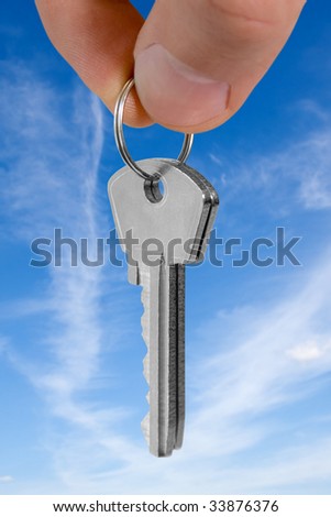 key in fingers over blue background. mortgage concept