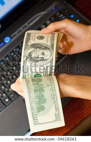 person shows money in hands near the laptop