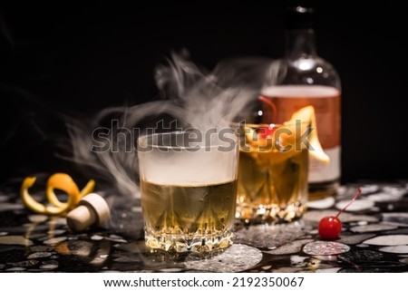 Smoke billowing out of an Old Fashioned cocktail, against a black background. 商業照片 © 