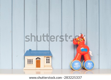 toy house and plastic horse on the bookshelf on blue wooden background in the children\'s room