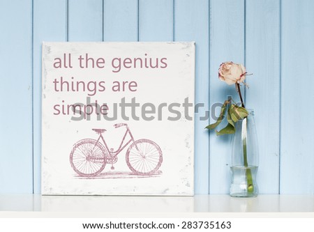 Motivating and inspiring  poster with quote All the genius things are simple and white rose in the bottle on blue wooden background