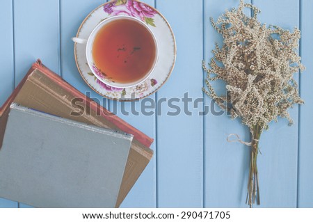 ancient books, black tea in china teacup and summer blooming bouquet