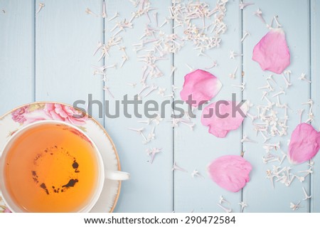 Black tea in china teacup,  lilac flowers and scattered petals of rose