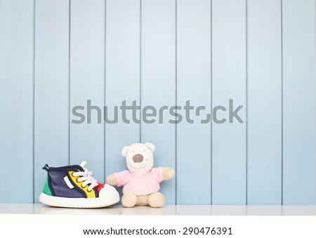 Tiny baby shoes and teddy bear on the table in baby\'s room