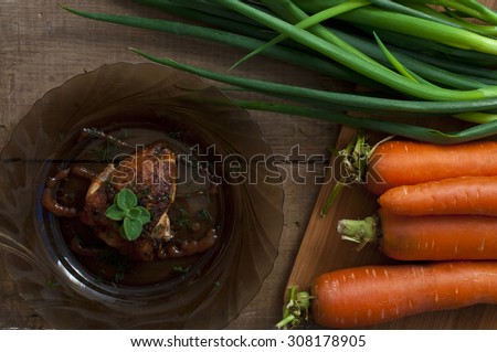 Chicken with crispy golden crust cooked in oven, green onions and carrots on wooden cutting board