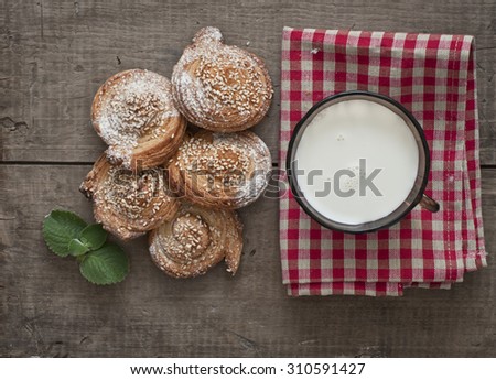 Festive sweets, puff cookies with sesame seeds, sugar candies and milk on gingham table cloth