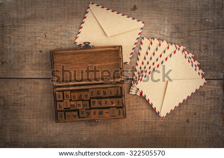 wooden stamps alphabet in old vintage box and ancient envelopes on autumnal dry maple leaves background