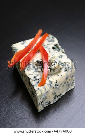 Red pepper slices on a block of cheese, isolated on black