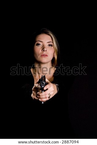 Sexy blond in sweater and jeans with semi-automatic handgun pointed at camera, looming out of darkness
