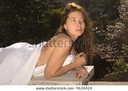 Attractive model lounging in birthday suit, wrapped in a sheet