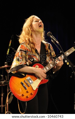 Attractive singing female guitarist playing at a life concert