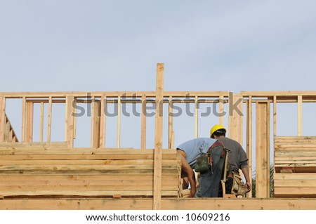 Hispanic construction worker picking up 2x4 blocking for installation