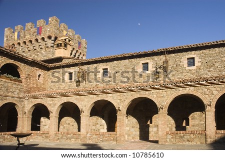 Late afternoon  sunlight on medieval Tuscan fortification Castle tower viewed from the inner courtyard with moon rising overhead