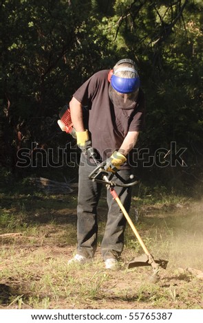 Active senior citizen gardener using a garden weed whacker to remove mountain misery from his yard