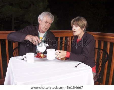 older couple in an outdoor restaurant enjoying dessert and coffee after dinner in the evening
