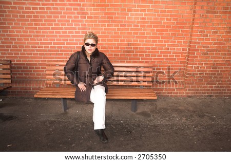 pretty woman outdoorsitting on a bench  in an old village in denmark with a wall   in red brick