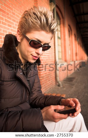 pretty woman outdoor in an old village in denmark with a wall   in red brick and mobile phone in hands