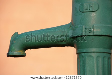 green manual water pump in front of a wall in denmark