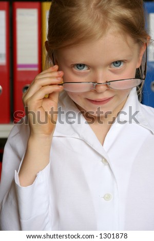 Little girl as businesswomen looking out of too big glasses