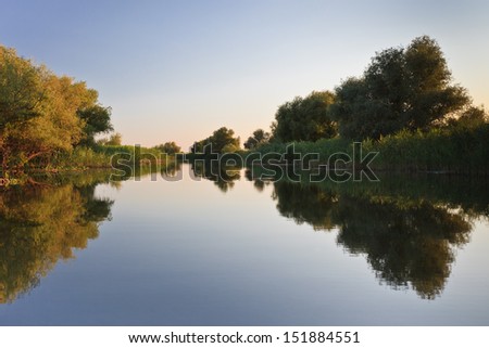 reflection of trees on a blue lake, Danube Delta, Romania