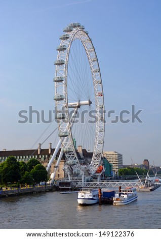 LONDON - JULY 17, 2013: Landmark London Eye tourist attraction viewed from London Bridge on the South Bank of the Thames River on July 17, 2013 in London.