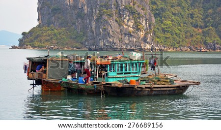 Ha Long Bay, Vietnam - April 17, 2015: People on a small wooden fishing boat moored in Ha Long Bay, Vietnam.