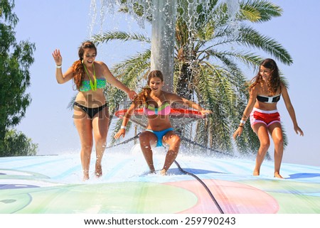 Rhodes, Greece-August 6,2014:Cheerful group of girls jumping on the wet bubble in the  water park  .Wet bubble is one of many popular game for adults and children in Water park