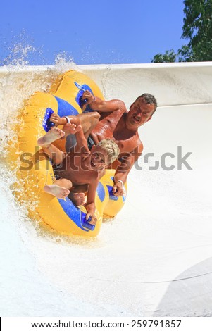 Faliraki,Rhodes, Greece-August 17,2014:Father and son drive with tube on the rafting slide in the  Water park.Rafting slide is one of many popular game for adults and children in Water park