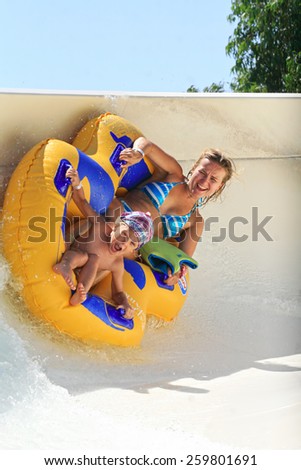 Faliraki,Rhodes, Greece-August 17,2014:Mom and daughter drive with tube on the rafting slide in the  Water park.Rafting slide is one of many popular game for adults and children in park