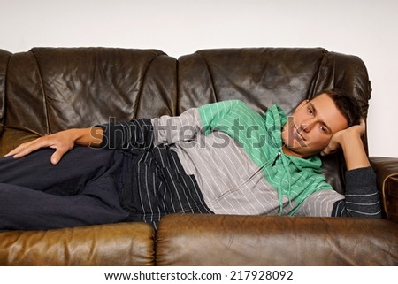 Young smiling man lying on couch relaxes