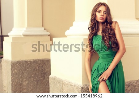 sexy lady in green dress standing near yellow wall at street