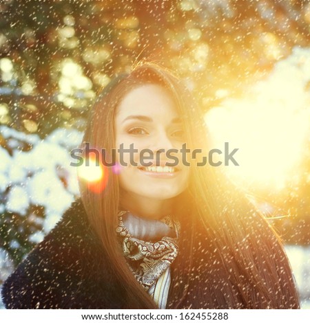 winter portrait of beautiful smiling woman with snowflakes in forest