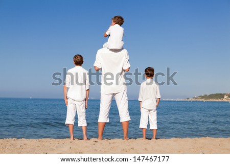 Back view of father and sons walking on beach, outdoor