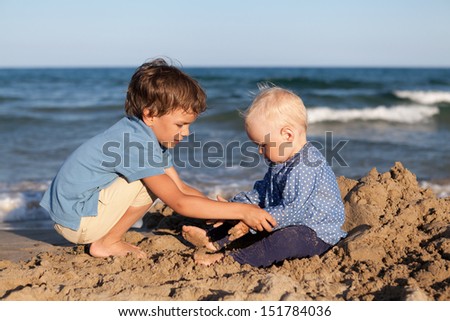 Happy brother and sister playing in the sand at the beach