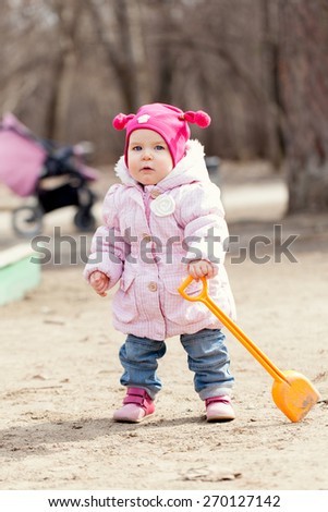Happy cute baby girl walks in spring park, first steps