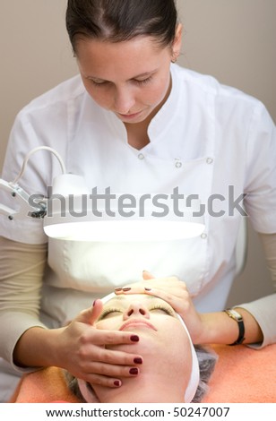 Woman in Cosmetic Cabinet under lamp. Faces skin cleaning.