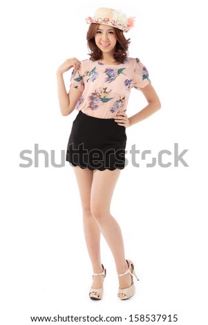 Asian woman full body posing in rosy pastel top and scallop edge skirt shorts with flower top hat isolated on white background.