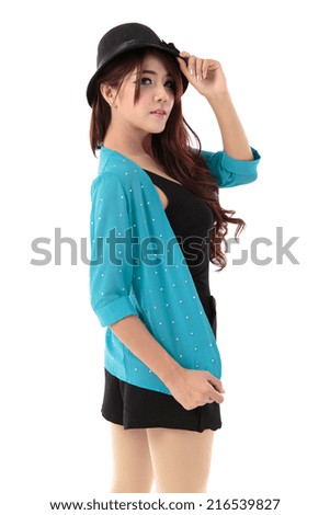 Asian woman posing in a black vest top and black skirt with black hat and cyan shade jacket isolated on white background.