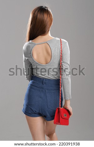 Asian woman pose in long sleeve deep v-neck drape top and high waisted denim shorts.