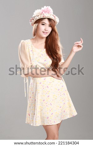 Asian woman posing in yellow shade graphic printed half peplum sleeve, wrapped waist dress with  hat.