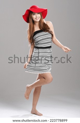 Asian woman in striped tube top and flare skirt set with red hat.